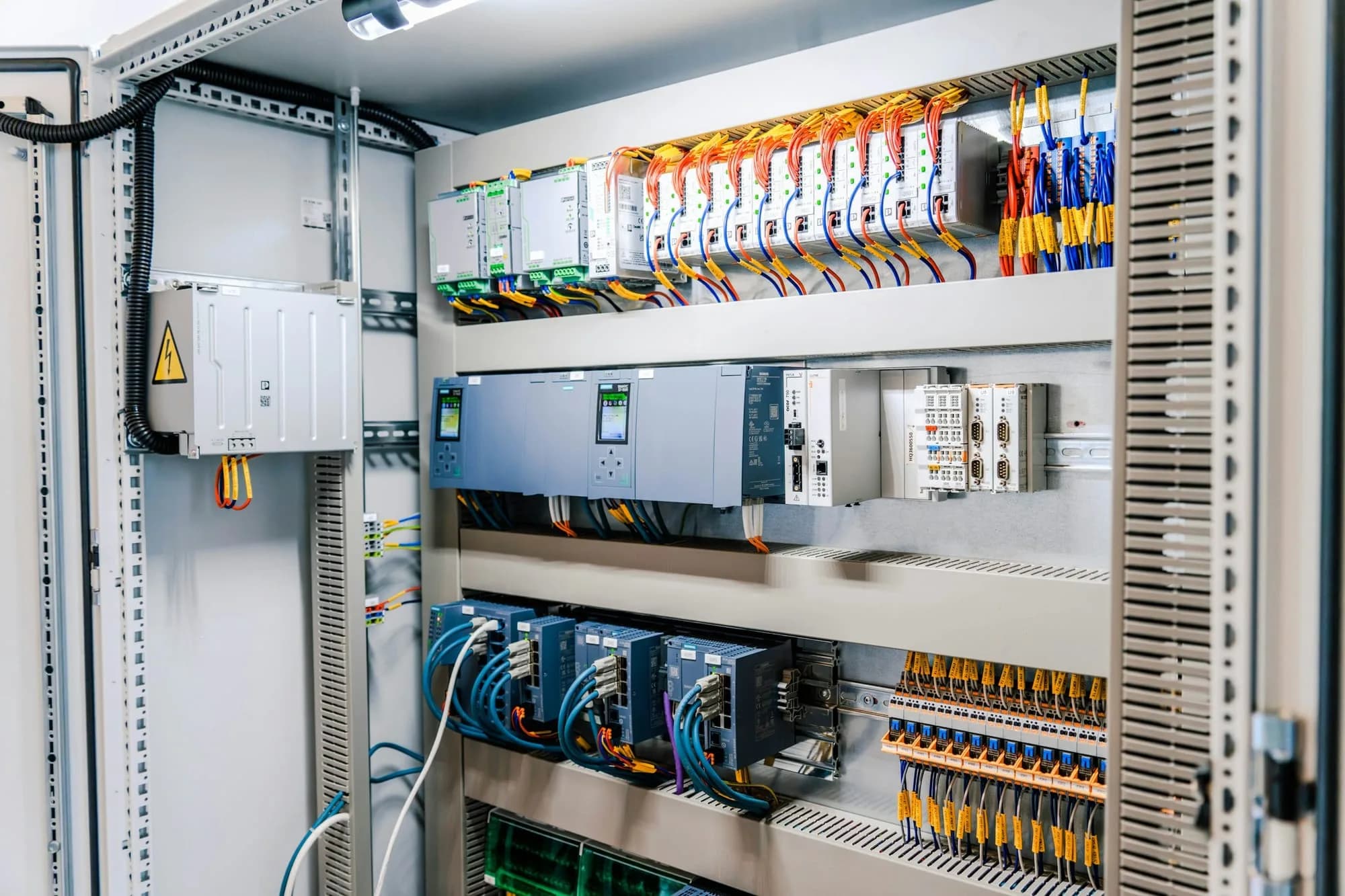 Tablero eléctrico industrial abierto, con módulos de control, borneras y cableado ordenado por colores